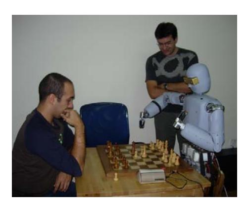 Two images of Arabot, the first standing (left) and the second performing autonomously chess playing against a human (right).